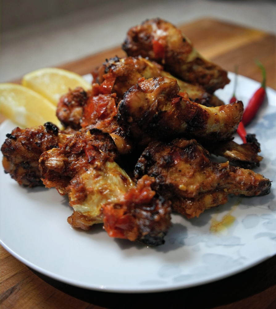 roasted peri peri chicken wings served with lemon wedges and chilies