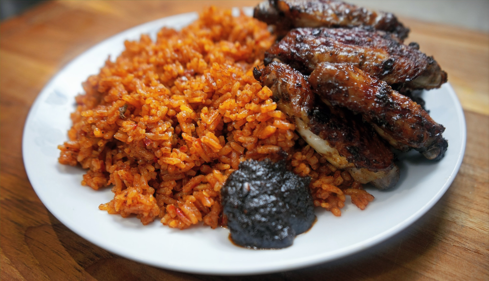 a plate of ghana jollof, fried chicken and some shito