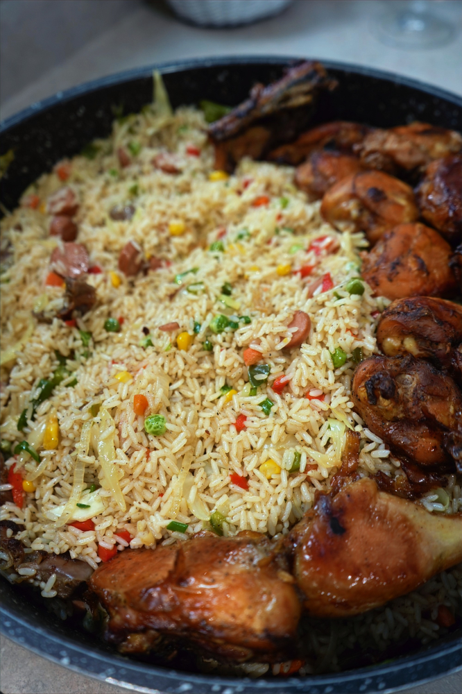 a pot of nigerian fried rice and fried chicken drumsticks