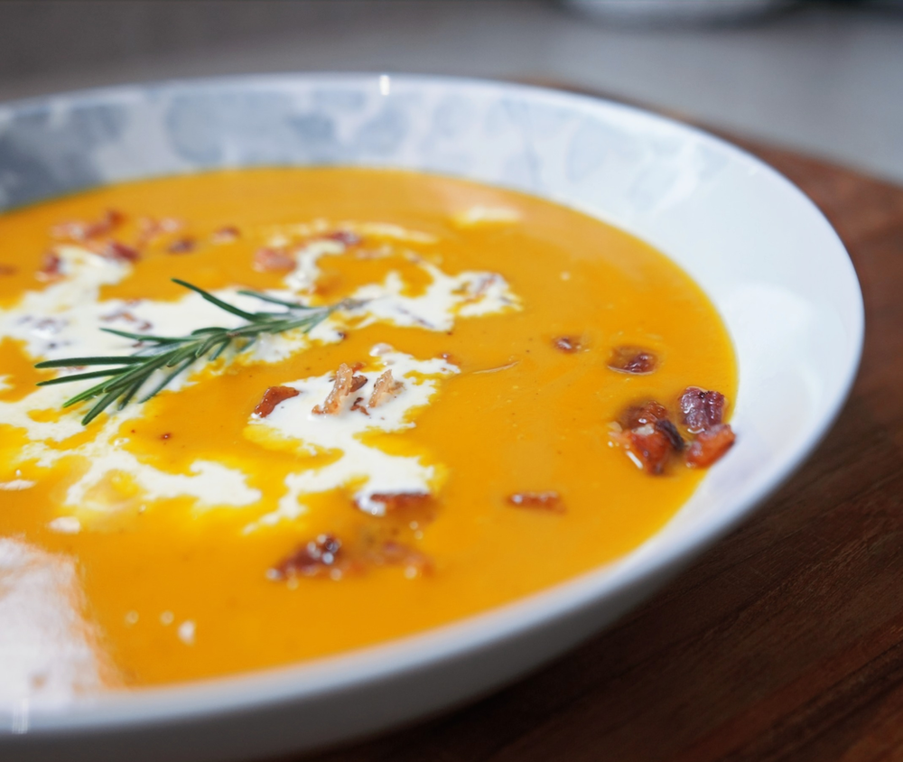 butternut squash soup garnished with rosemary, bacon and heavy cream