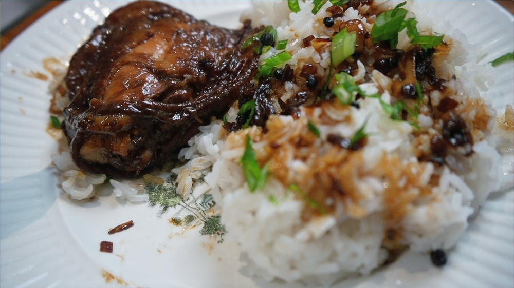 cooked white rice and chicken adobo sauce garnished with spring onions