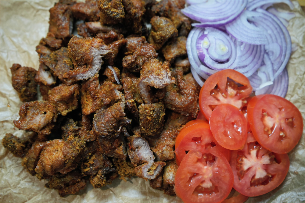 Nigerian lamb suya served with sliced tomatoes and onions