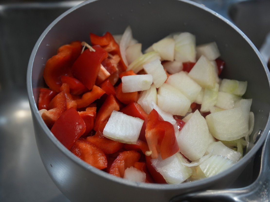 pot of cut-up red bell peppers, scotch bonnets and onions