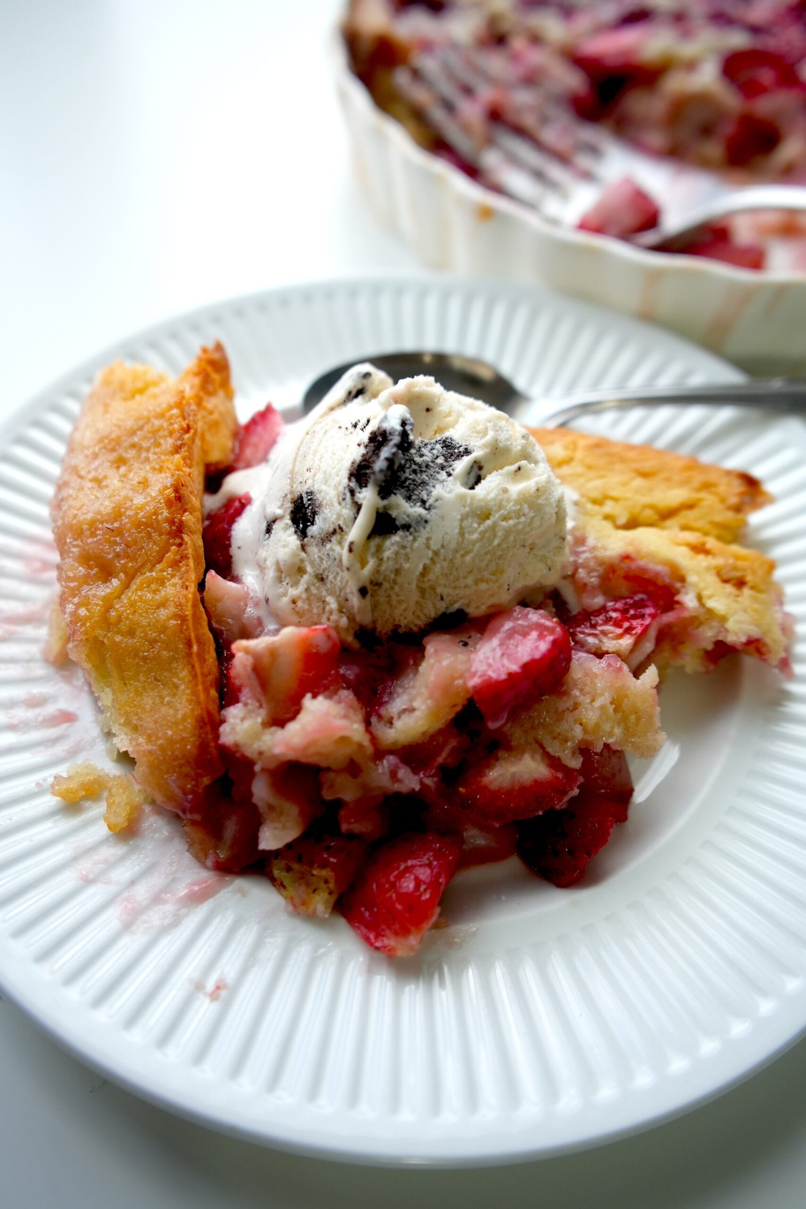 A dessert of fresh strawberry cobbler topped with ice cream