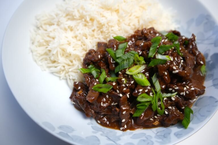 mongolian beef garnished with spring onions and served with white rice