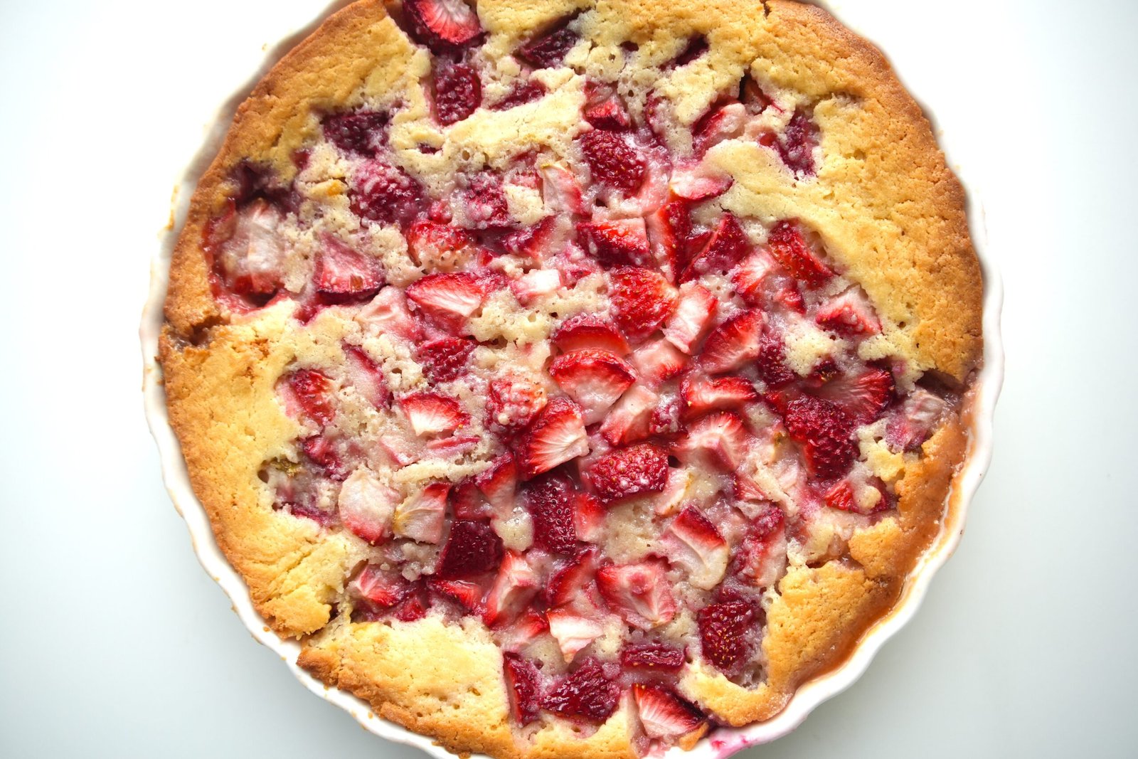 Fresh strawberry cobbler in a white ceramic dish.