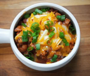 a bowl of chicken chili topped with cheese and spring onions