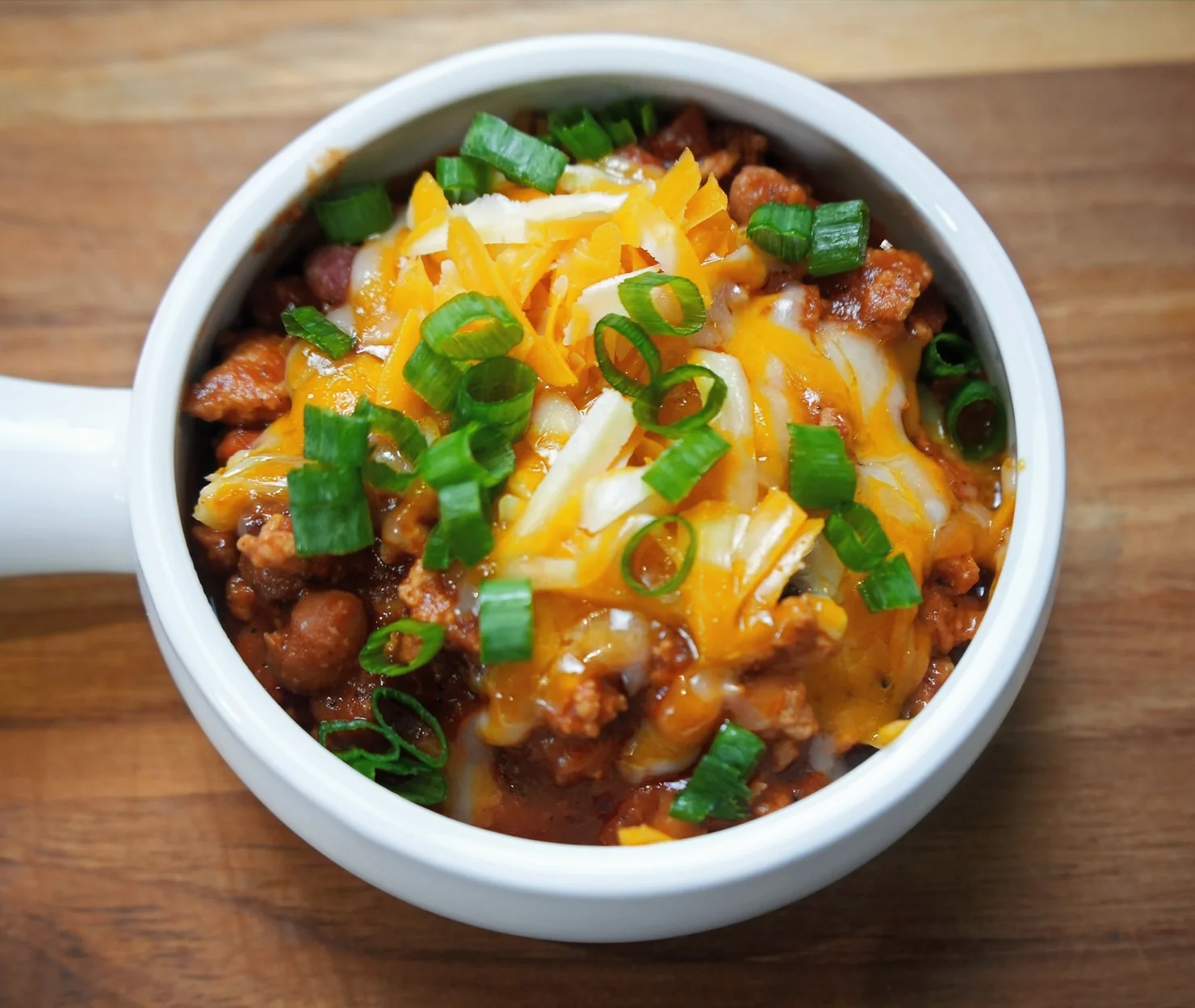 chicken chili served in a bowl garnished with cheese and spring onions