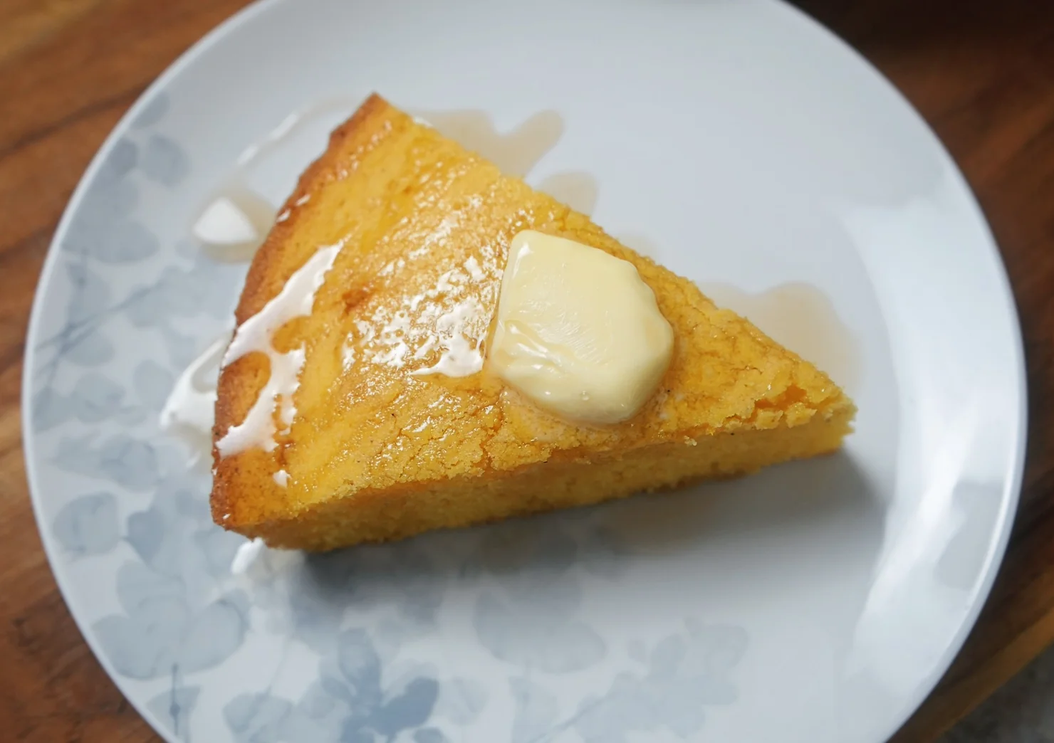 a slice of buttery cornbread topped with maple syrup and butter