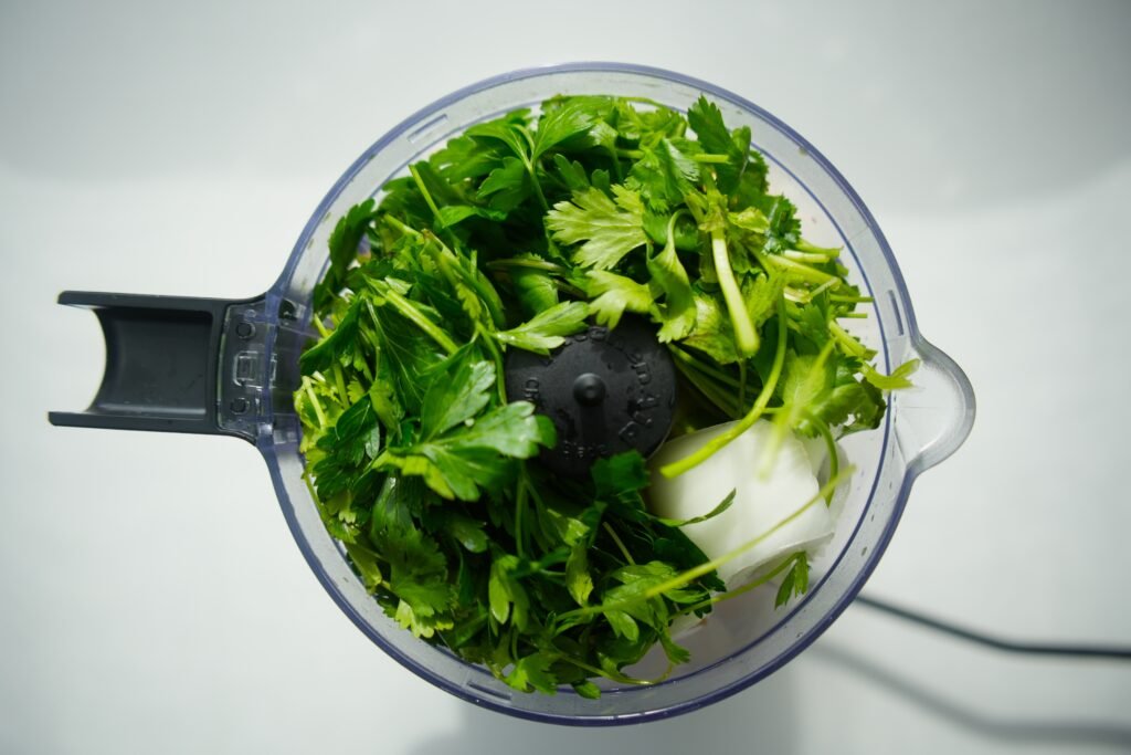 a food processor cup filled with parsley and cilantro